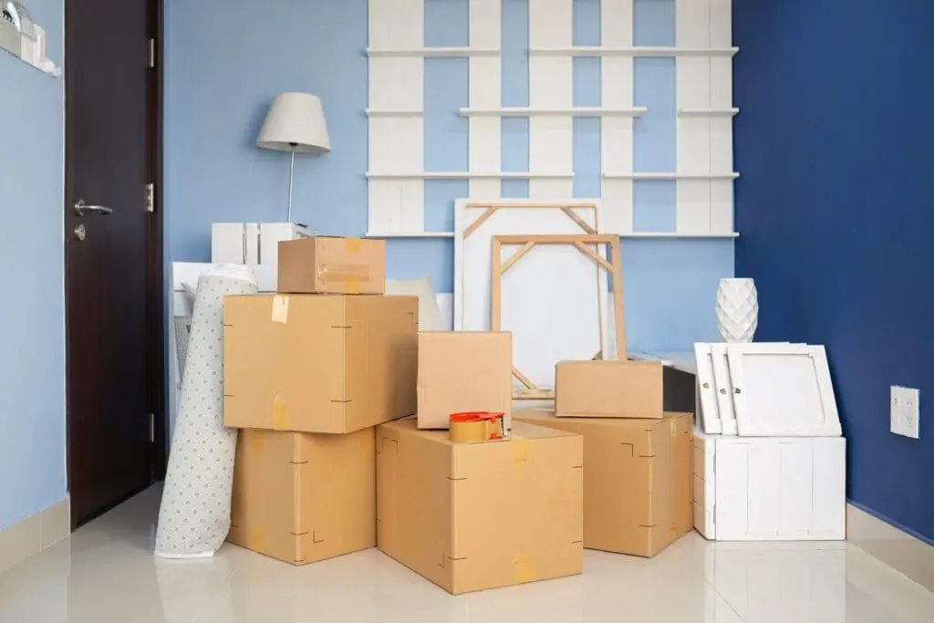 Plusieurs cartons contenant des affaires et meubles dans une pièce vide d’un nouvel appartement